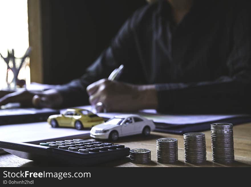 Car insurance and car service. Businessman with stack of coins and toy car, business and financial concept.