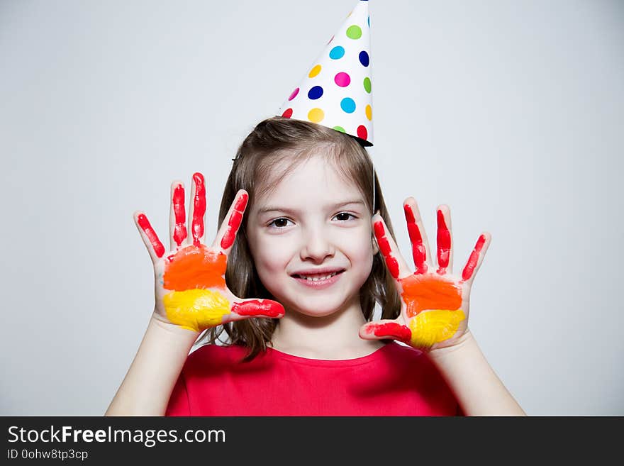 Child in a bright dress and cap, showing her hands painted in bright colors. Child in a bright dress and cap, showing her hands painted in bright colors