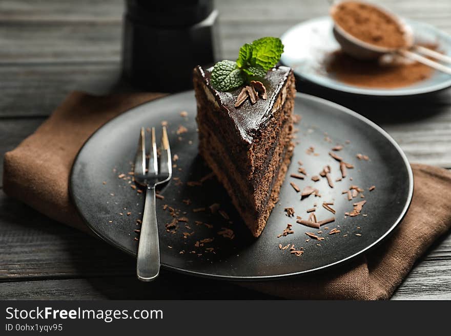 Plate with slice of chocolate cake and fork on wooden table