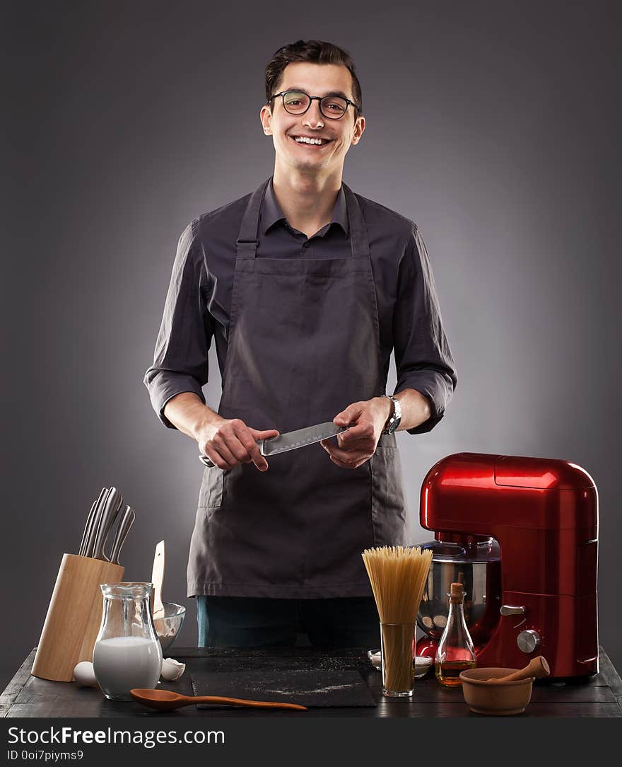 Handsome man prepares a delicious dish on a gray background. Studio photo