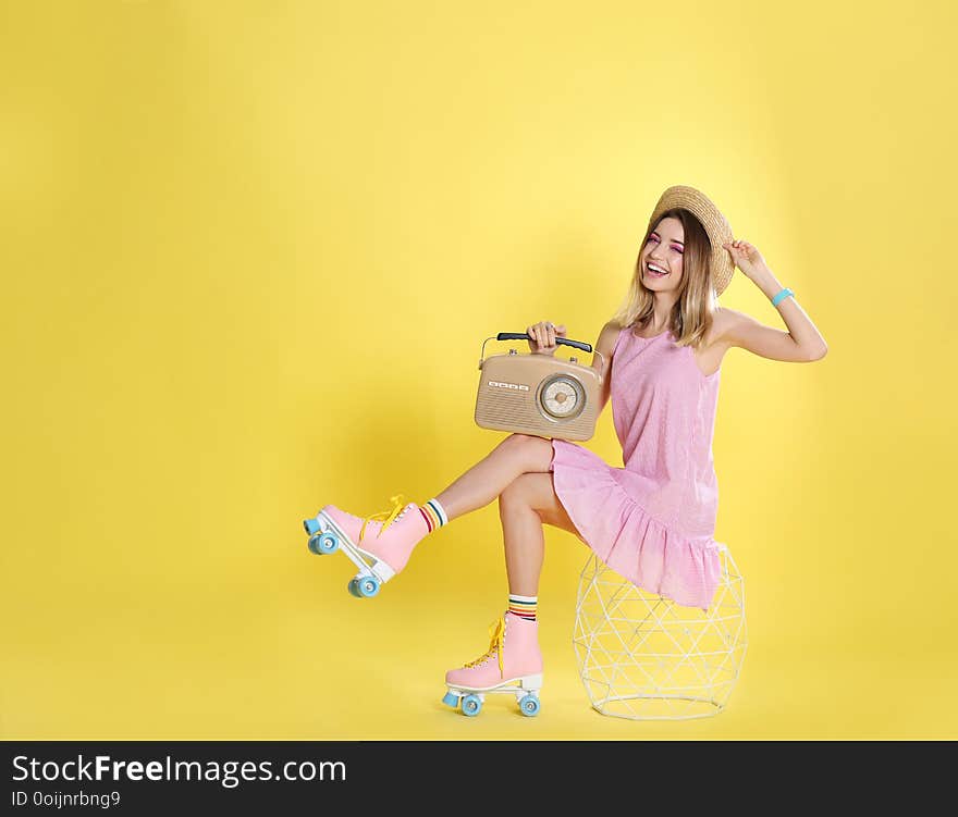 Young woman with roller skates and retro radio on color background, space for text