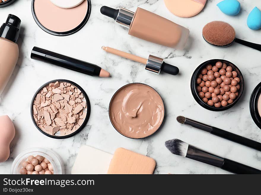 Flat lay composition with skin foundation, powder and beauty accessories on marble background