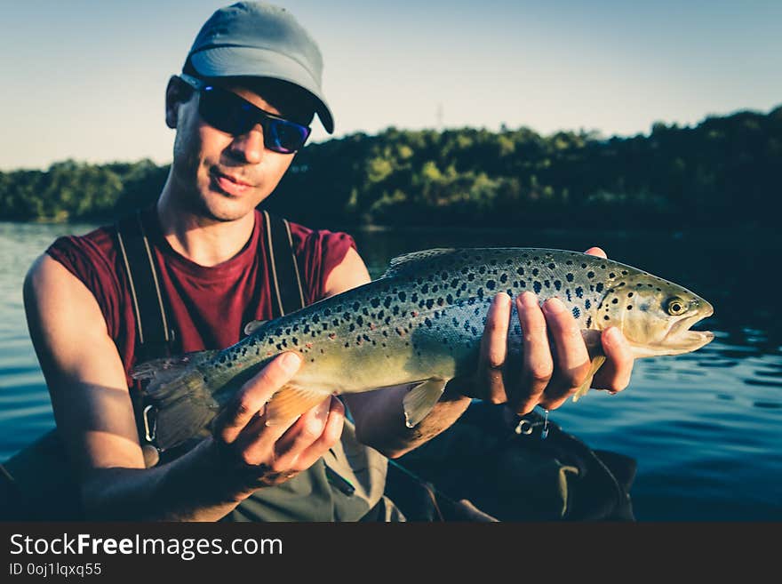 Fisherman with catch of big Brown Trout on lake in Jesenice, Slovenia. Sunny summer day. Still water fly fishing and outdoor lifestyle theme. Fisherman with catch of big Brown Trout on lake in Jesenice, Slovenia. Sunny summer day. Still water fly fishing and outdoor lifestyle theme