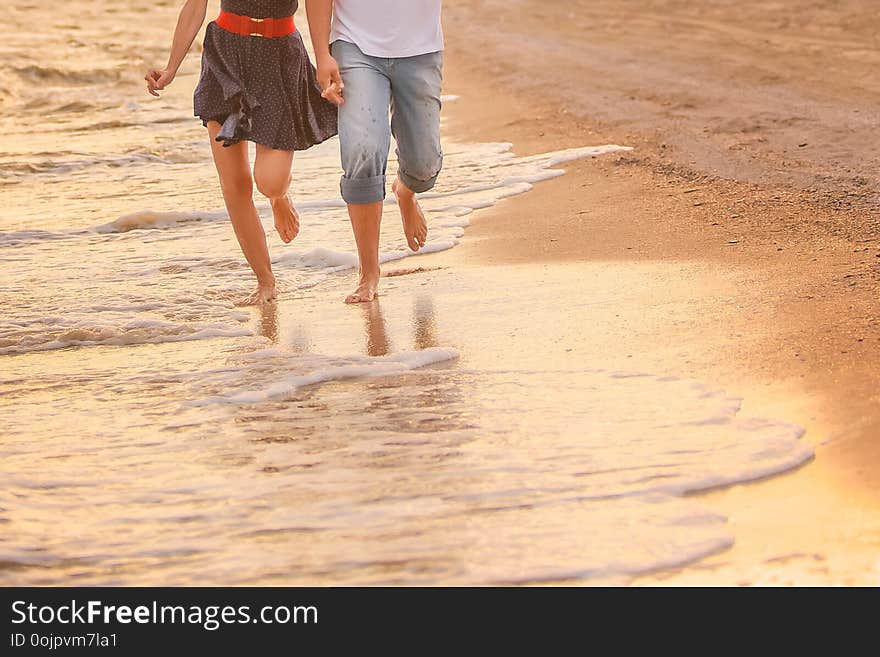 Couple in love runs barefoot on the sea along the surf at sunset. honeymoon, valentine, happiness and love. with copy space for text