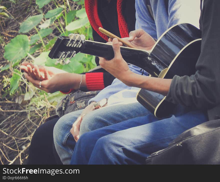 Friends playing guitar in park