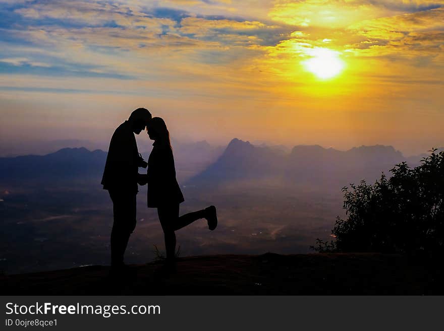 Silhouette of happy young couple in love looking view sunset on the mountain. Romantic couple in love