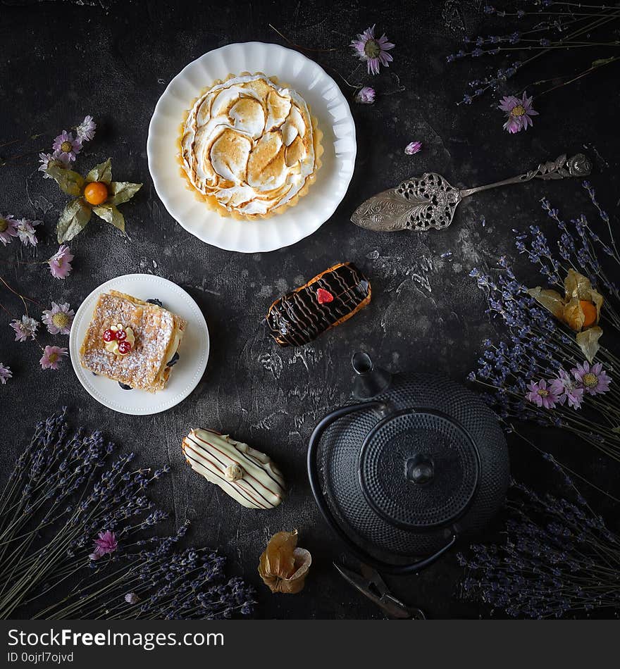 Tea and sweets on a dark background, Mille-feuille, Eclairs, Tart, Decorative with flowers, Top view, Vintage