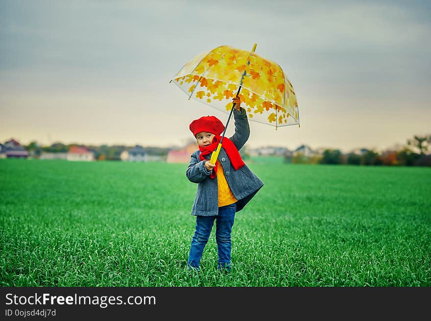 A child on a walk with a bright umbrella in the spring in the field. A child on a walk with a bright umbrella in the spring in the field