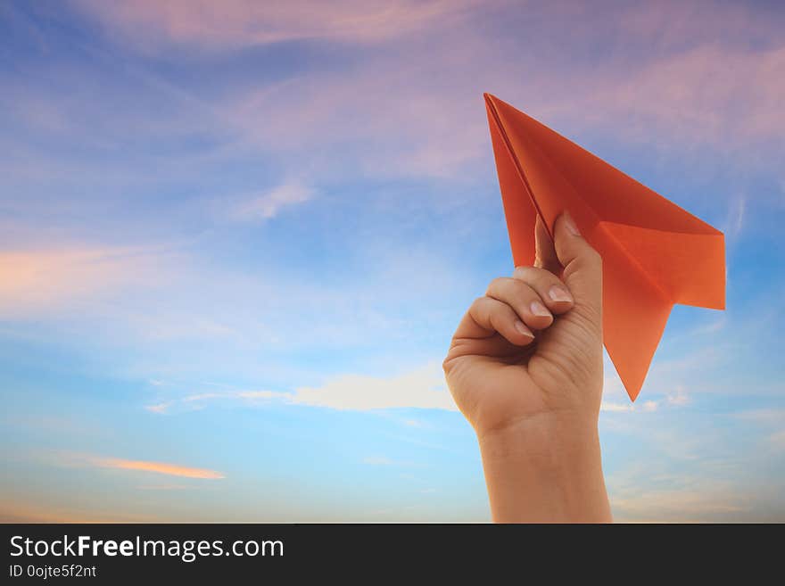 Woman Hand holding red paper rocket with blue sky background. freedom concept