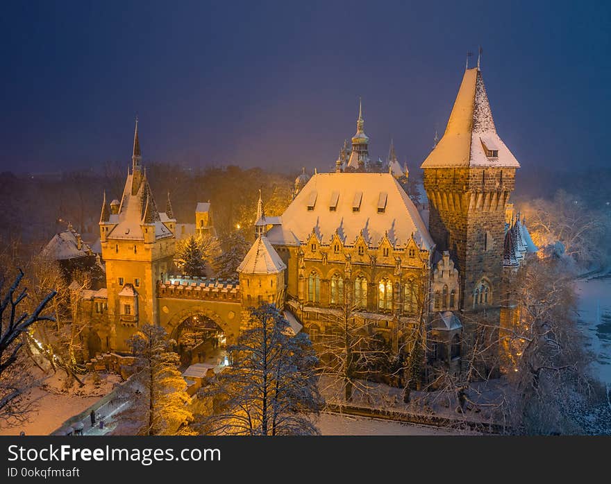 Budapest, Hungary - Aerial winter scene of the beautiful Vajdahunyad Castle in snowy City Park at blue hour during snowing