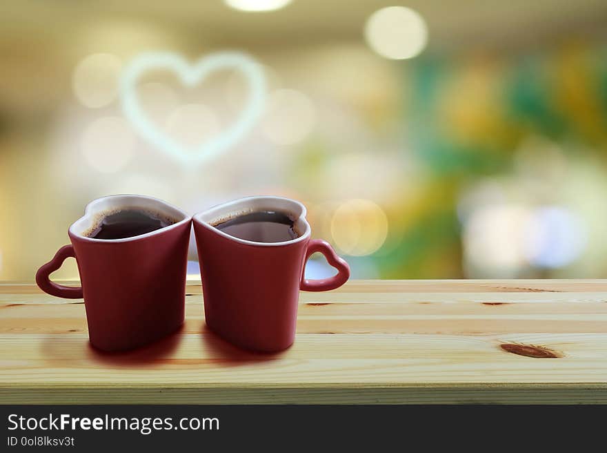 Black coffee in two pink cups heart shape with smoke is a heart shape on wooden floor and Colorful bokeh background