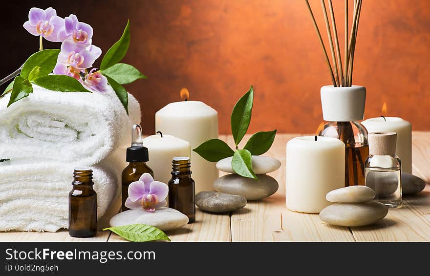 Composition with orchid and jasmine flowers, some small bottles with essential oil, candles and light stones for massage. Composition with orchid and jasmine flowers, some small bottles with essential oil, candles and light stones for massage