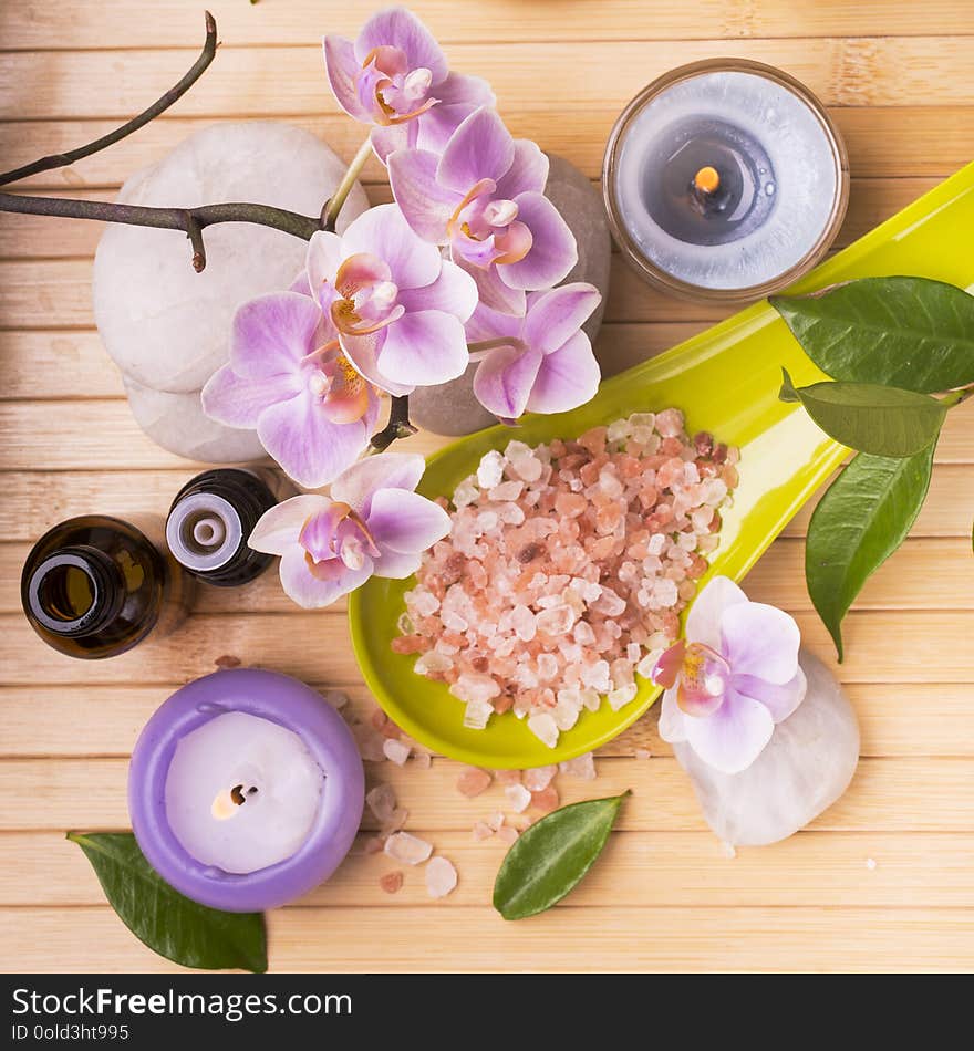Spa.Composition with orchid flowers, some small bottles with essential oil, pink salts, candles and light stones for massage. Spa.Composition with orchid flowers, some small bottles with essential oil, pink salts, candles and light stones for massage