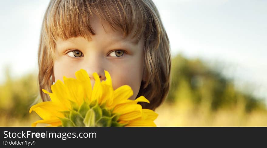 Happy boy with sunflower outdoors.