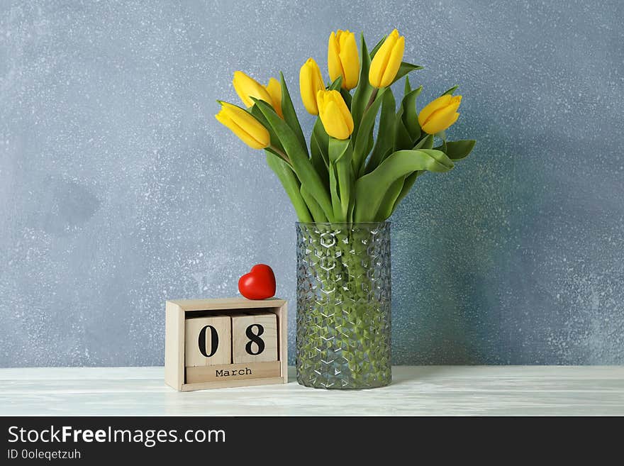 Beautiful yellow tulips in a glass vase on white background for Mother`s Day