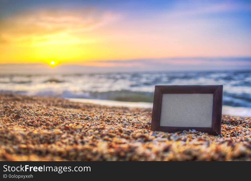 Photo frame on sand background in summer, sea at sunset place for lettering, copy space