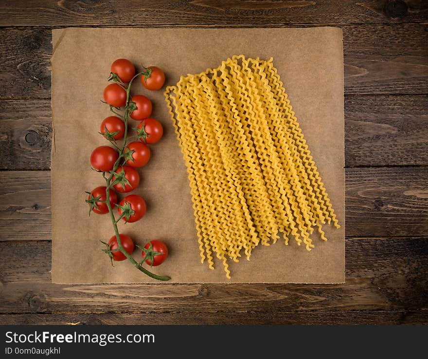 Pasta And Tomatoes On Dark Wooden Background With Copy Space. Top View