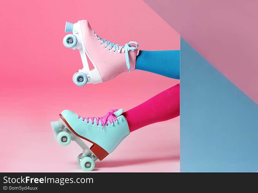 Woman with vintage roller skates on color background, closeup