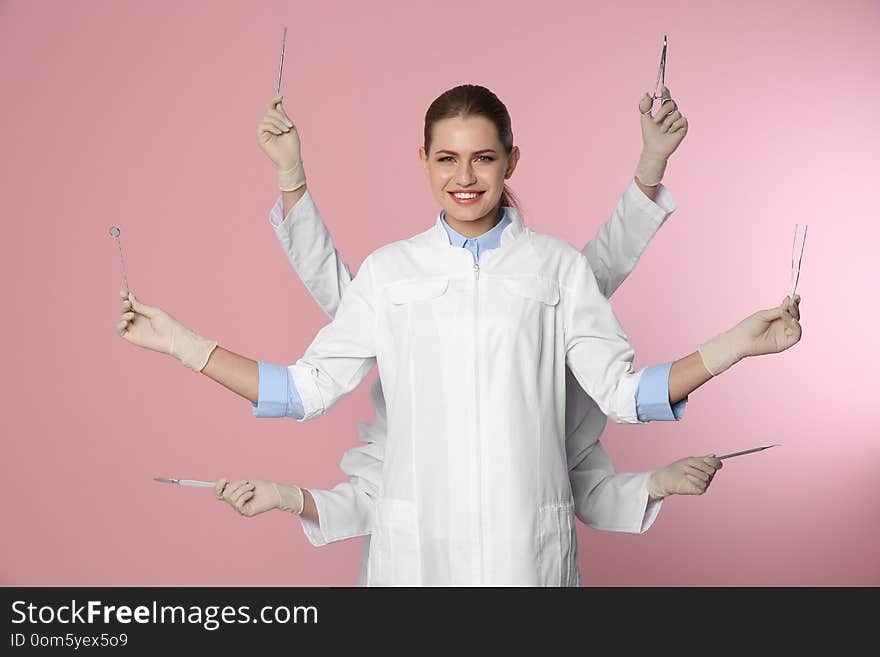 Female dentist with multiple hands holding tools on color background