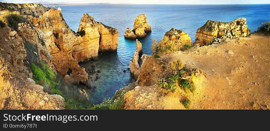 Amazing panoramic view of Ponte de Piedade in Algarve, Portugal, red and yellow majestic cliffs rising over the waters of the Atlantic ocean, fascinating seascape near the town of Lagos