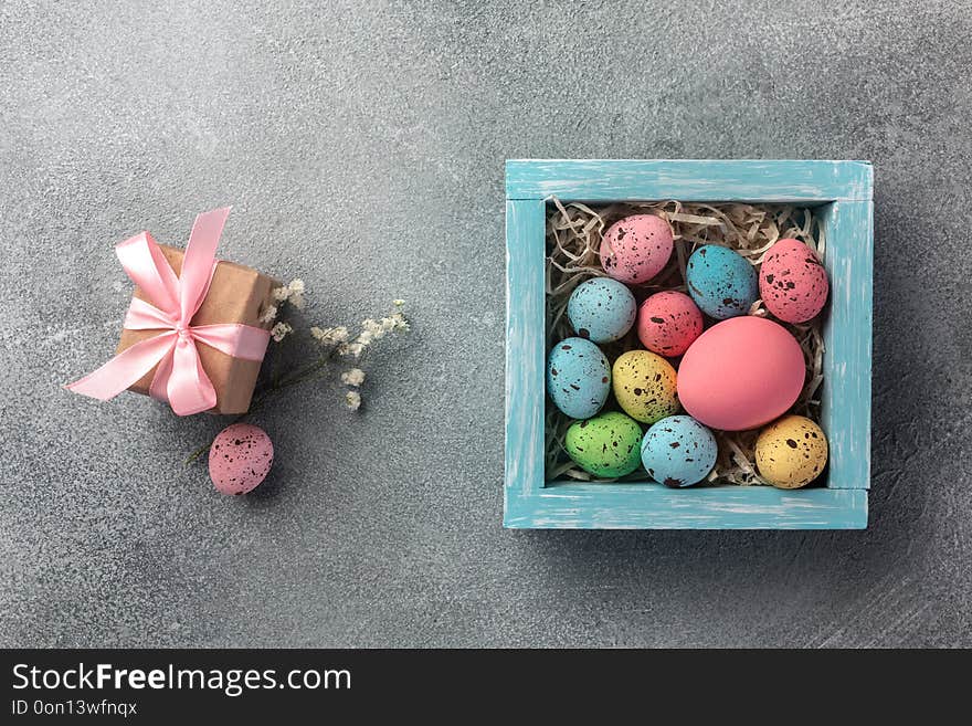 Colorful easter eggs in box and gift on table. Top view with copy space.