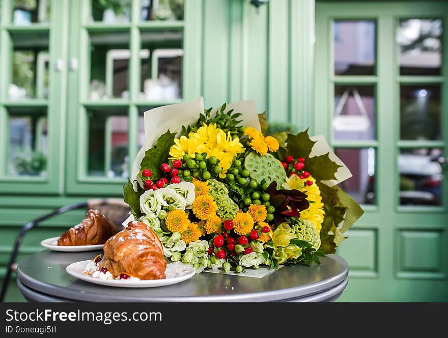 Bouquet of colorful flowers and dessert on table. Alstromeriya, lotus, hypericum, eustoma, celosia