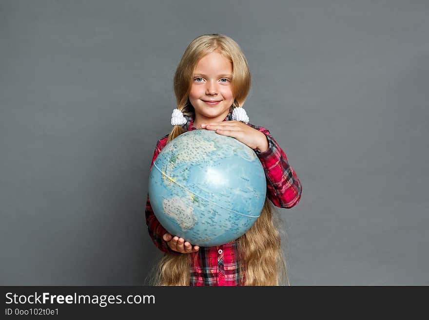 Little girl with two ponytails studio standing isolated on grey wall holding globe traveling around the world looking camera smiling positive. Little girl with two ponytails studio standing isolated on grey wall holding globe traveling around the world looking camera smiling positive