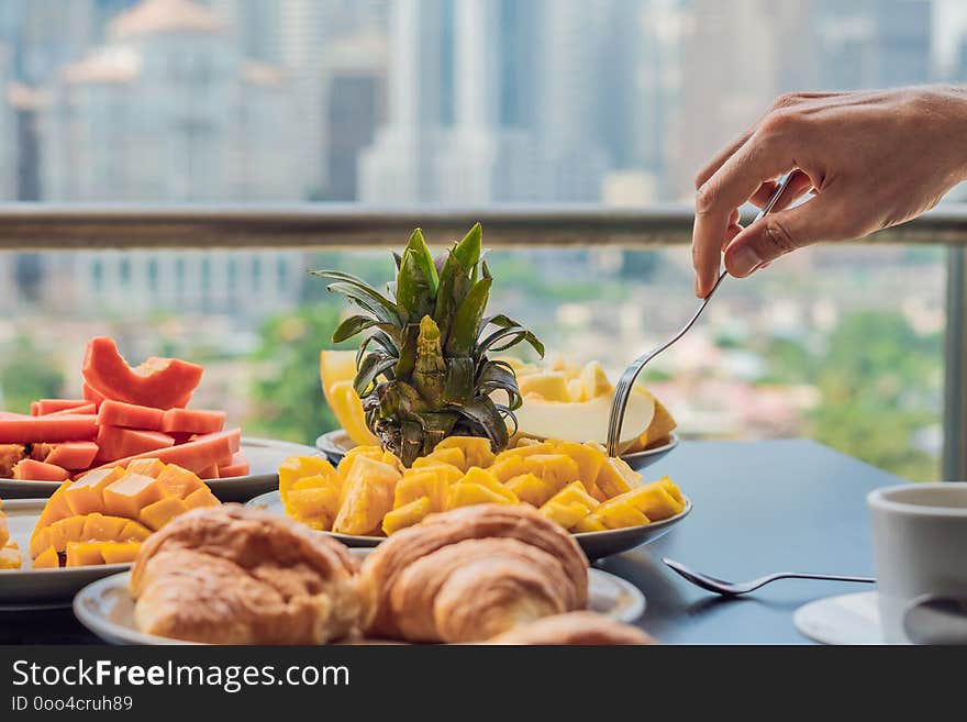 Breakfast table with coffee fruit and bread croisant on a balcony against the backdrop of the big city.