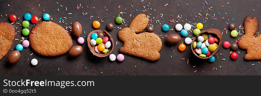 Easter greeting card backdrop with colorful gingerbread cookies, chocolate eggs and candies. Top view on stone table