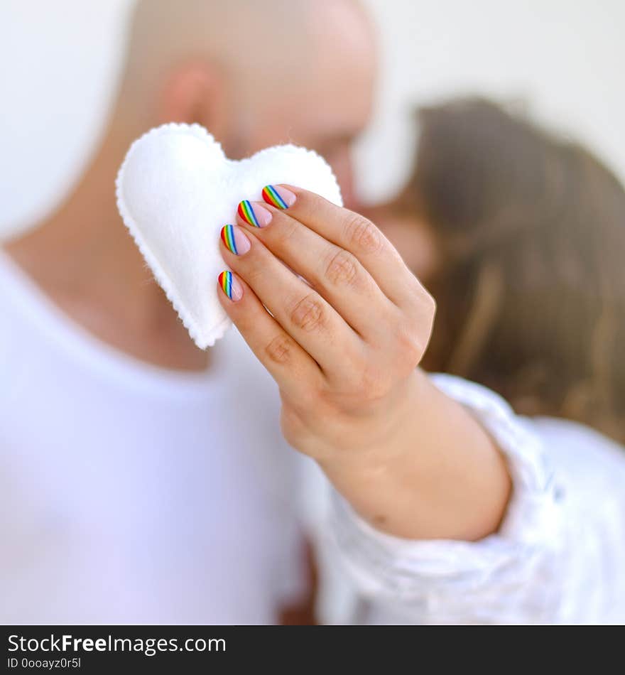 Young copule kissing and holding white felted heart. Love, valentine, lgbt, pride concept