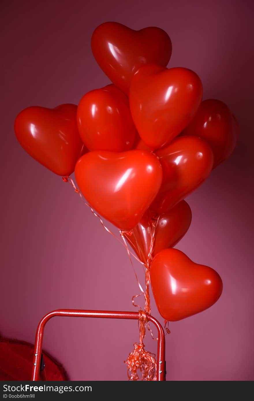 Red heart-shaped balloon on a pink background.//