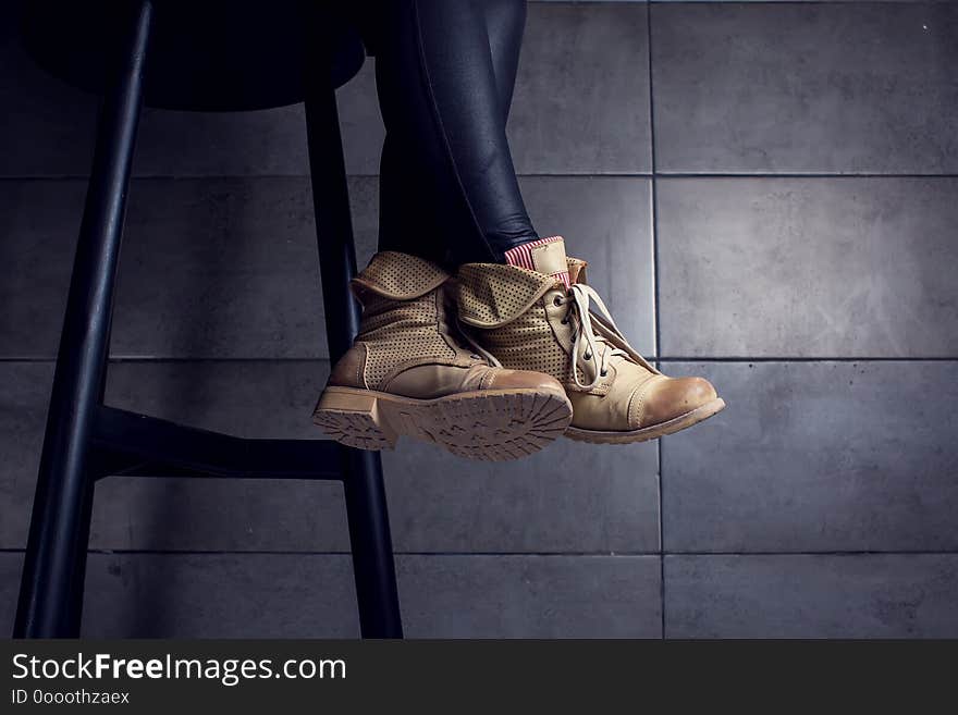 Low section of woman wearing boots sitting at bar counter in cafe