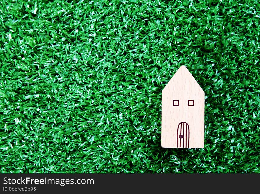 Wooden house model on artificial grass floor. Property investment and house mortgage concept