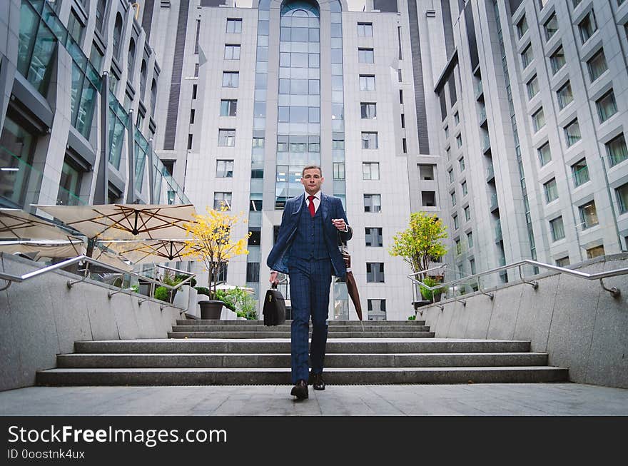 Serious businessman in a checkered stylish suit coming down the stairs. Business life in the city. Portrait of a modern businessman