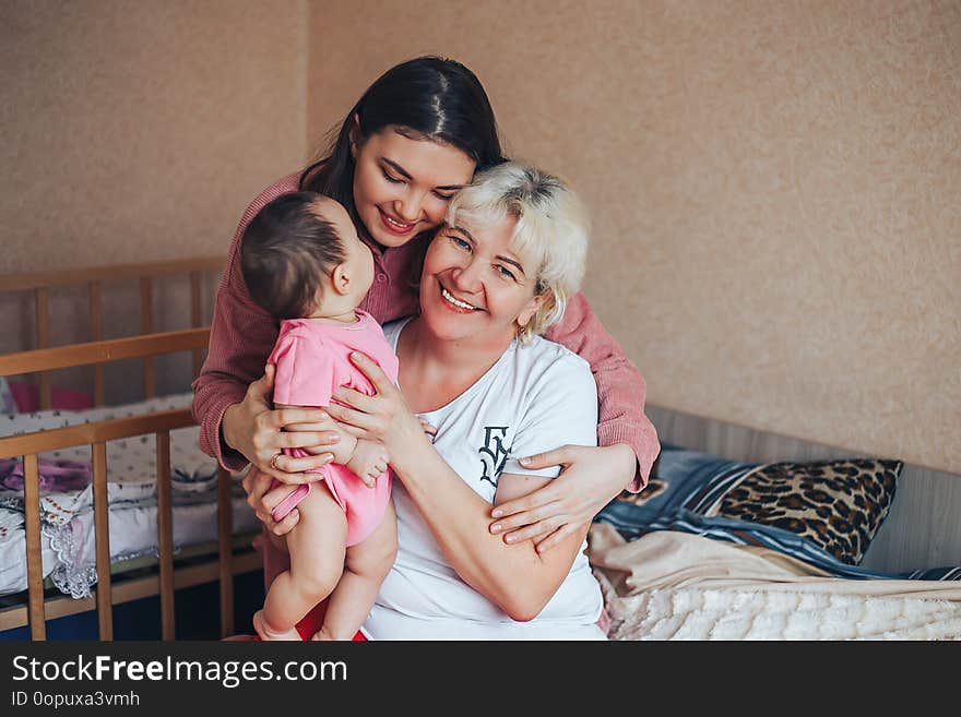 Little cute girl, her attractive young mother and charming grandmother are spending time together at home. Women& x27;s generation. Happy International Women& x27;s Day