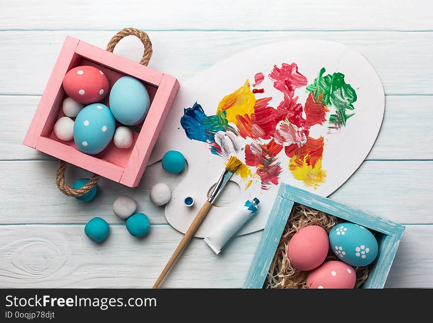 Easter background with colorful eggs, paints, brushes on stone gray. Top view with copy space.