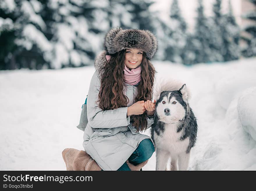 girl in fur hat with black and white husky