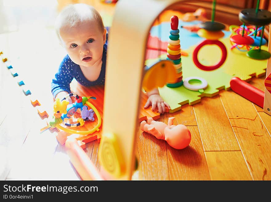 Baby girl playing with toys on the floor. Happy healthy little child at home