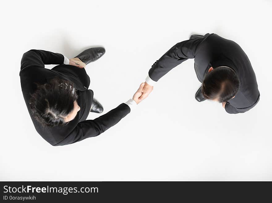 Close up top view of two Asian business men in suit and white shirt, black shoes, standing and handshaking on business agreement, on white isolated background. Close up top view of two Asian business men in suit and white shirt, black shoes, standing and handshaking on business agreement, on white isolated background