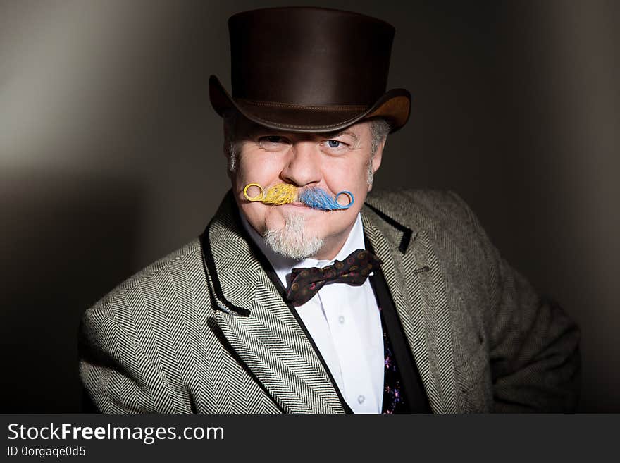 Mustache is an adult male artist in a business suit and a cylinder hat. Playful wreath