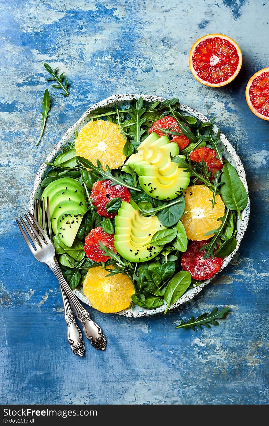 Citrus salad with mixed greens and blood orange. Vegan, vegetarian, clean eating, dieting, food concept. Blue stone background