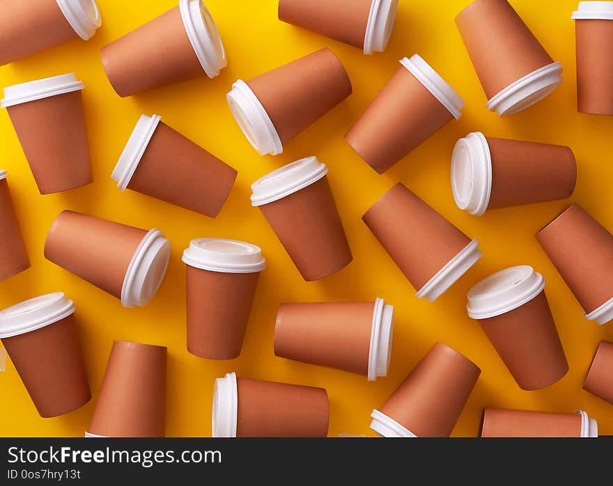 Multiple disposable coffee cups organized over yellow background