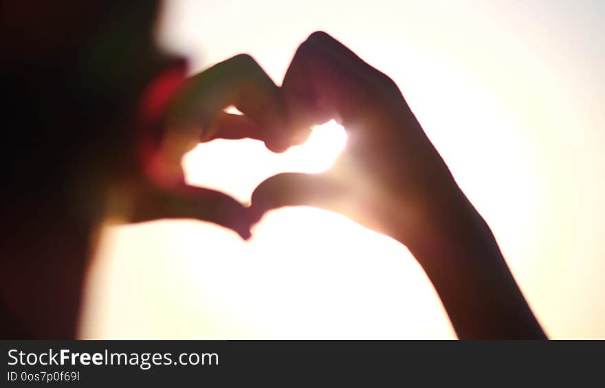 Boy making heart with hands over sunset background. Silhouette hand in heart shape with sun inside. Vacation concept. Summer holidays. Tourism, have fun