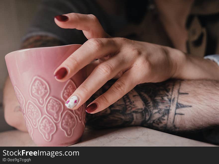 Close up young beautiful curly french woman drinking tea of coffe form pink ceramic cup. Close up young beautiful curly french woman drinking tea of coffe form pink ceramic cup