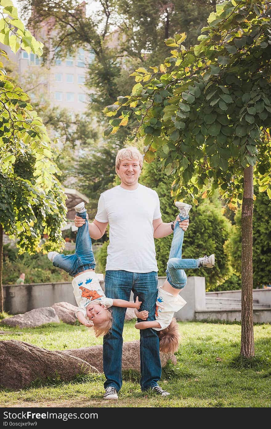 Happy father with his little son in park in sunny day. Dad holds son head down. Happy father with his little son in park in sunny day. Dad holds son head down