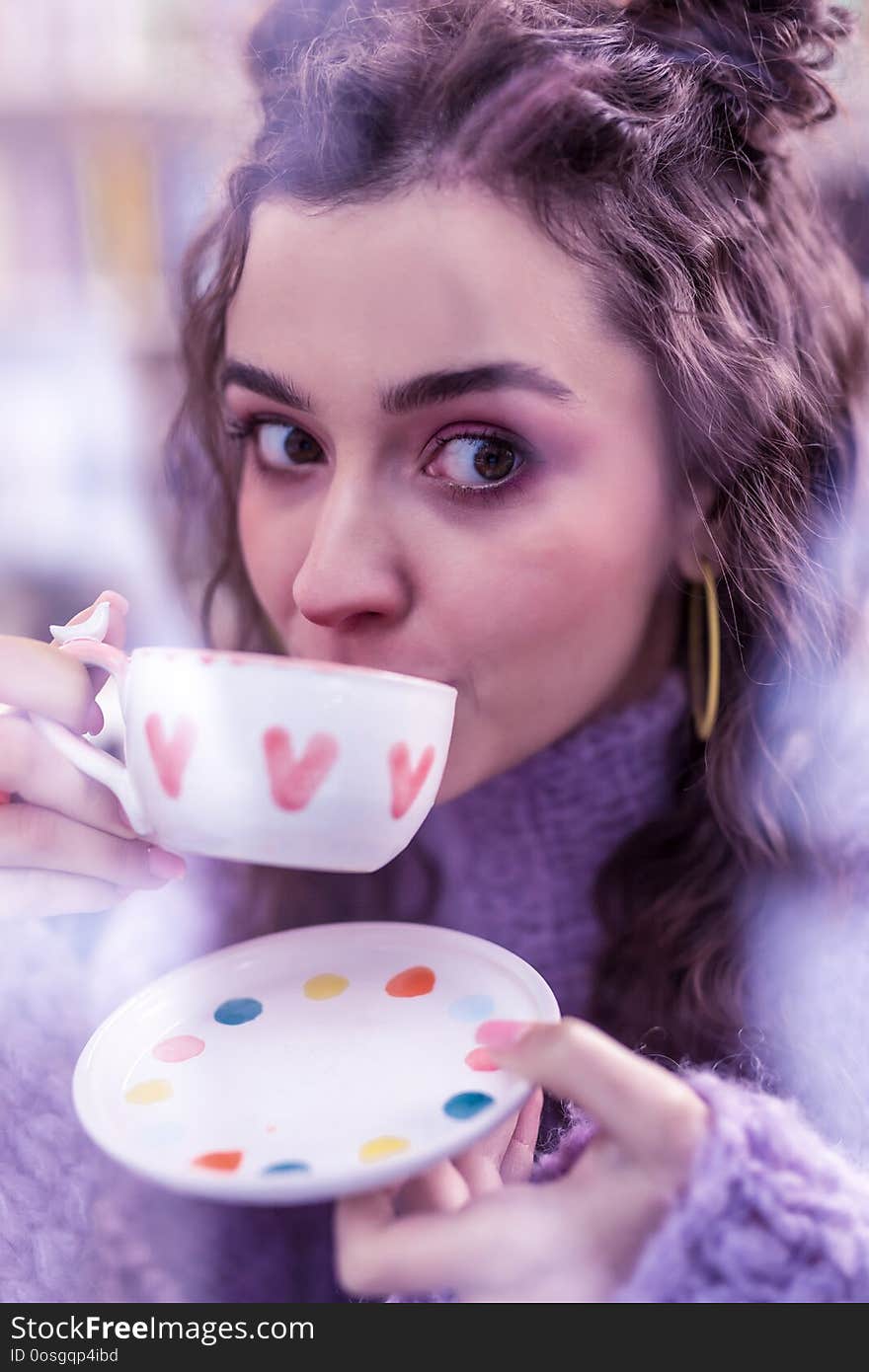 Appealing dark-haired woman with big brown eyes sipping tea