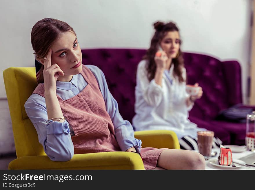 Describing situation. Skeptical unhappy girl in pink dress being unsatisfied with absence of attention from her friend. Describing situation. Skeptical unhappy girl in pink dress being unsatisfied with absence of attention from her friend