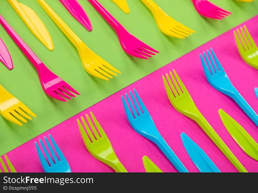 Composition of colorful plastic cutlery on a bright background top view. Composition of colorful plastic cutlery on a bright background top view