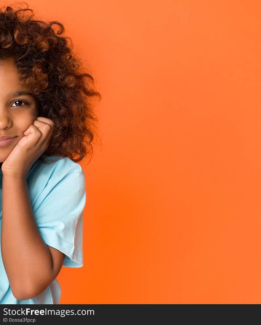 Half face portrait of schoolgirl with dark curly hair over orange background