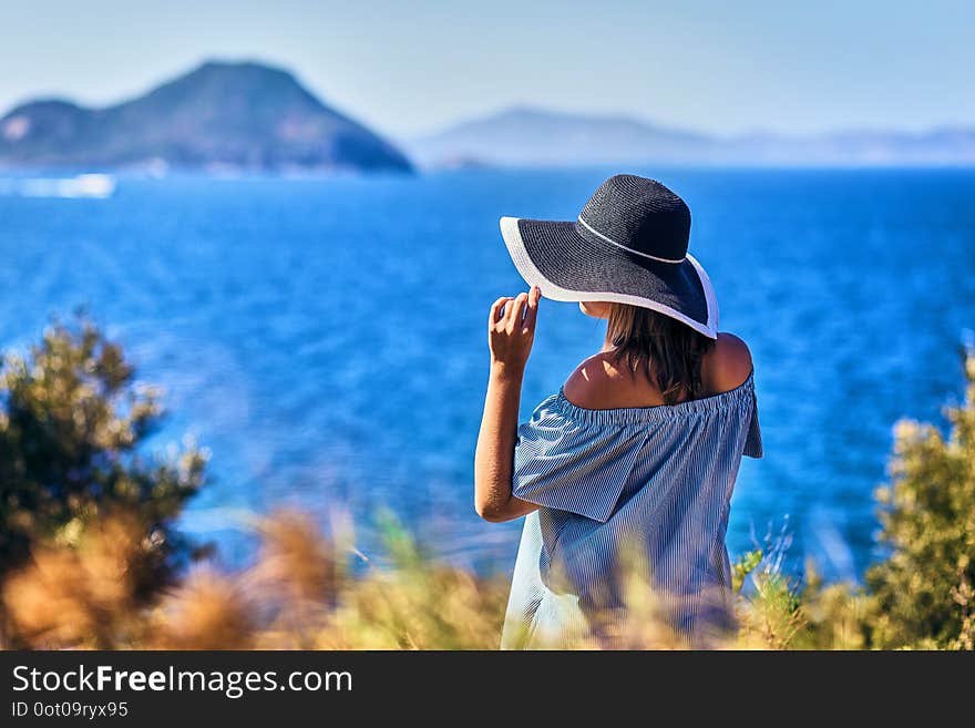 Beautiful woman in beach hat enjoying sea view with blue sky at sunny day in Bodrum, Turkey. Vacation Outdoors Seascape Summer